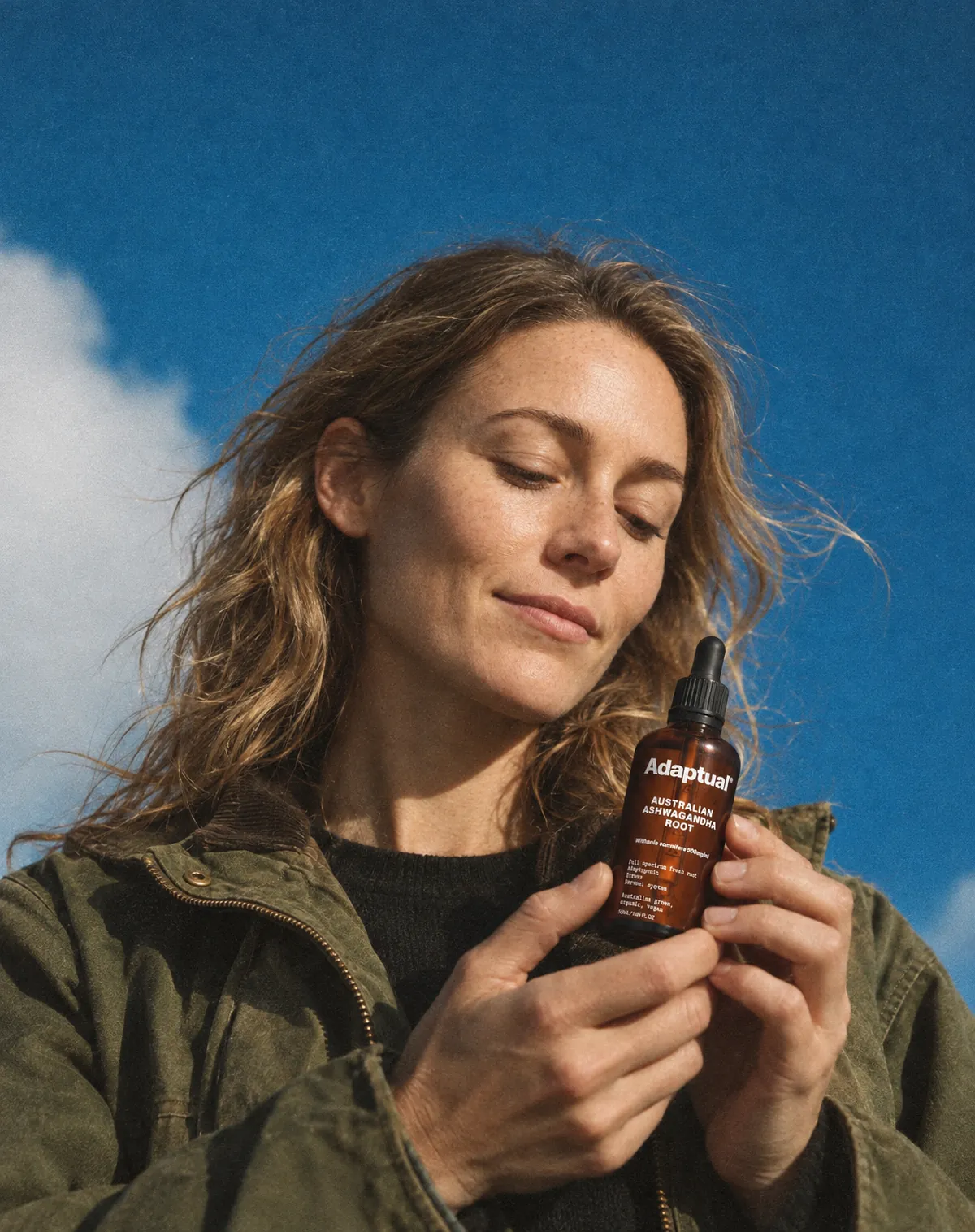 A woman in a field jacket looks down at the bottle